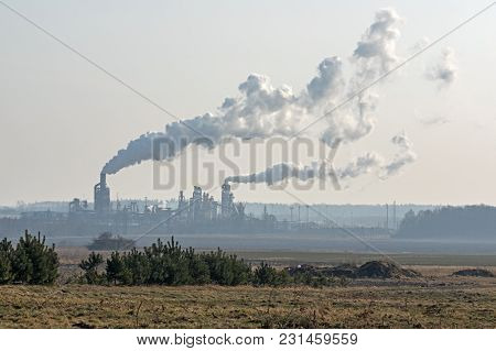 A Vast, Flat Area. In The Distance You Can See A Factory, A Shiny Metal Structure .. From The Chimne