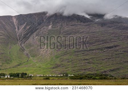 Annat, Scotland - June 10, 2012: Massive Brown-green Mountain Wall With Top In Clouds. Fine Line Of 