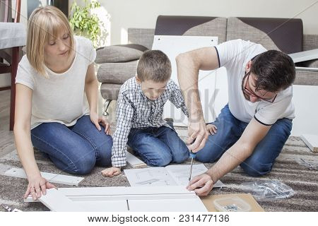 The Family Turns Furniture In The Living Room On The Carpet. My Father Screwed The Screw With A Scre