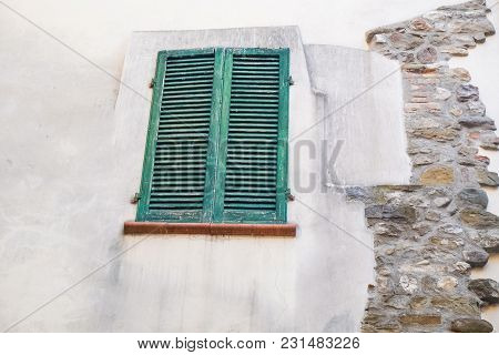 Green Window And Blinds Outside A Weathered Facade Of A White Home In Montone Italy
