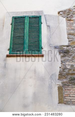 Green Window And Blinds Outside A Weathered Facade Of A White Home In Montone Italy