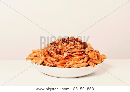 a plate with an assortment of different cooked pasta served with tomato sauce on a white table against a white background, with a blank space on top