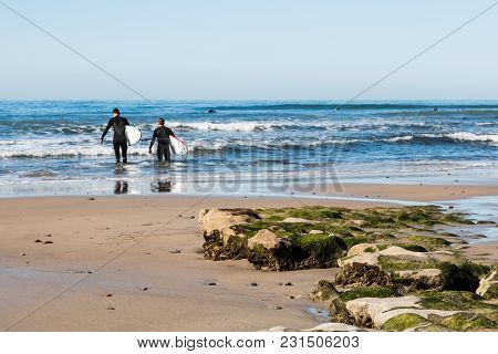 Encinitas, California/usa - February 24, 2018:  Two Male Surfers Head Out To Sea Holding Surfboards 