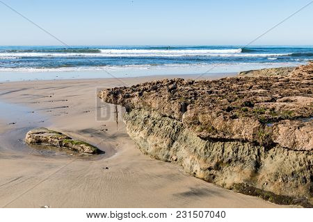 Swamis Beach In Encinitas, California At Low Tide, Revealing A Rocky Reef Covered By Barnacles.