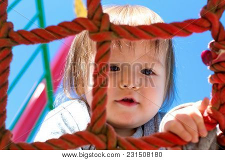 Multracial Toddler Boy Climbing On A Playground Ropes