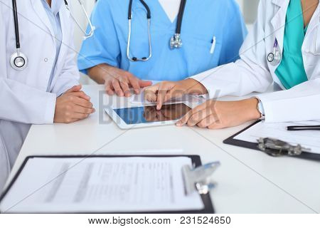 Group Of Doctors At Medical Meeting. Close Up Of Physician Using Touch Pad Or Tablet Computer.