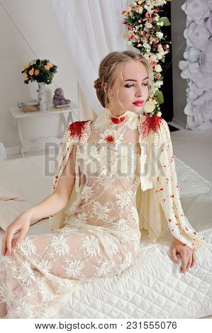 Young Girl In Beautiful Lingerie Sitting On White Bed. Portrait. Vertical Orientation