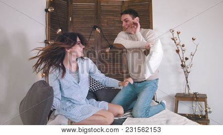 Happy Cheerful Loving Couple Having A Fight In Bed, Girl Tickling Guy