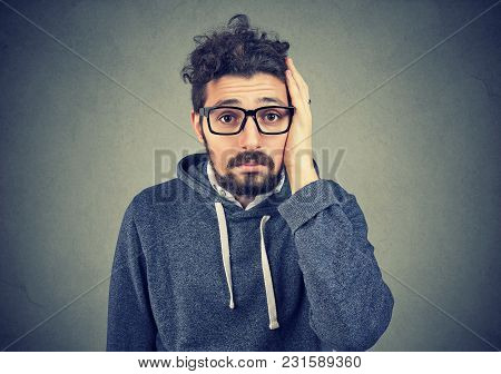 Portrait Of Disappointed Stressed Bearded Young Man On A Gray Background. Negative Human Emotions