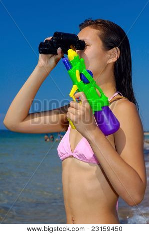 Kobieta z wody pistolet patrząc przez lornetki na plaży