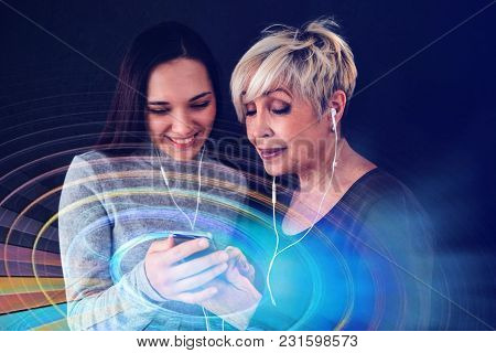 An Elderly Woman And A Young Girl Listen To Music Together. Communication Between People Of Differen