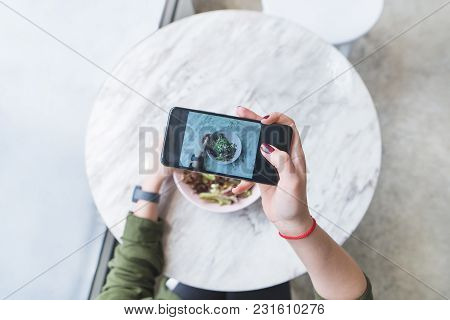 A Woman Makes A Photo Of Her Food At The Restaurant At The Table. The Blogger Picks Up A Salad At Th