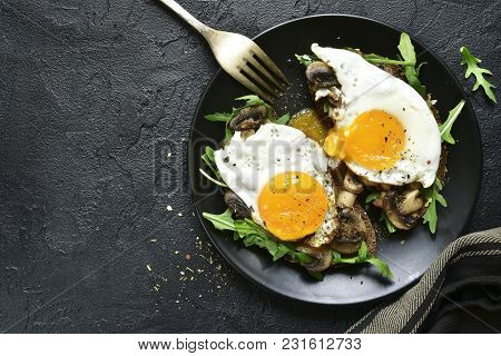 Whole Grain Toasts With Sauteed Mushrooms, Fried Eggs And Arugula Leaves.top View With Copy Space.