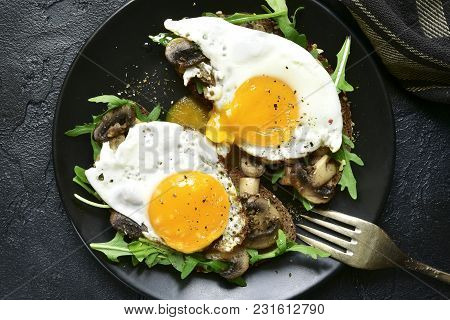 Whole Grain Toasts With Sauteed Mushrooms, Fried Eggs And Arugula Leaves.top View With Copy Space.