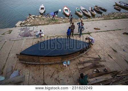 VARANASI, INDIA - MAR 13, 2018: Boatmen on the banks of Ganga river. One of the oldest cities in the world, considered a Holy city for Buddhists and Jains, as the center of Earth in Hindu cosmology.