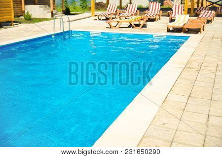 A Pool With Chaise Longues In Hotel