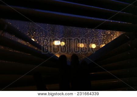 Rain Bokeh In A Window. Nigth City. Rain Drops On Glass. Look Through Blinds