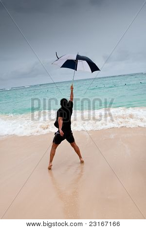 Opálený muž skok s deštníkem v modré moře pod šedou oblohou