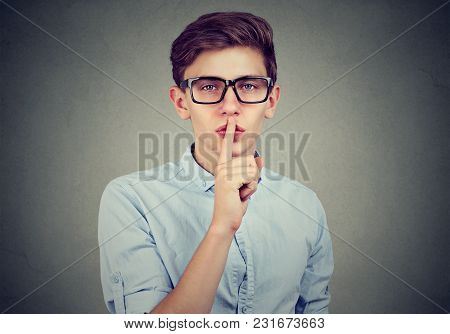 Secret Guy. Man Saying Hush Be Quiet With Finger On Lips Gesture Looking At Camera Isolated On Gray 