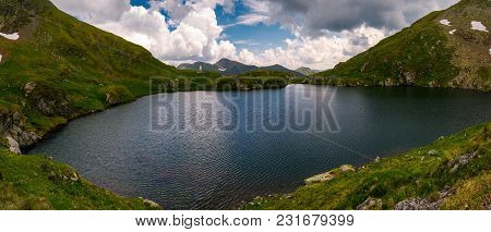 Panorama Of Capra Lake, Romania. Gorgeous Landscape Of Fagarasan Mountains On A Cloudy Summer Day