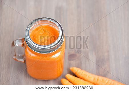 Healthy Carrot Smoothie In A Jar With Tube On Wooden Background. Shallow Dof