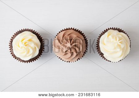 Cupcakes With Whipped Chocolate And Vanila Cream, On White Wooden Table. Picture For A Menu Or A Con