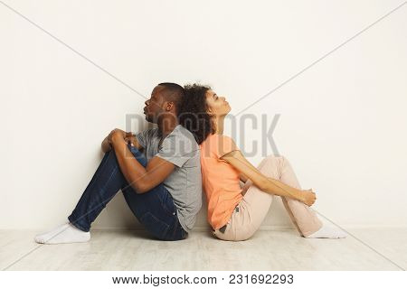 African-american Family Couple Sitting On Floor Back To Back In New Apartment After Discussing Inter