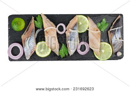 Herring Fillet With Lemon, Onion And Herbs On Black Slate Isolated On White Background. Top View