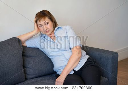 Loss Of A Loved One. Sadly Depressed Elderly Woman At Home, Sitting On The Couch. A Very Unhappy Wom