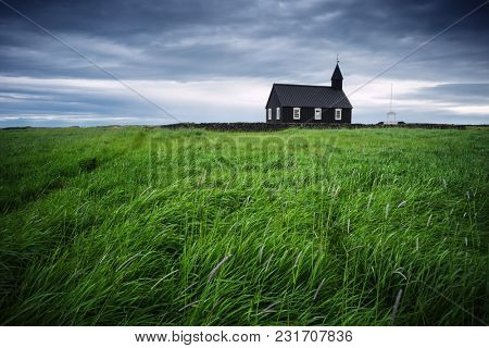 Black wooden church Budakirkja. Famous tourist attractions of Iceland near the village Budhir. Landscape in bad weather with a terrible stormy sky