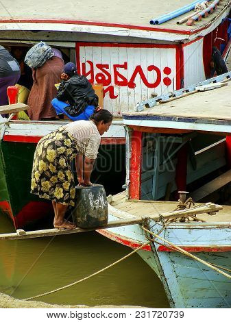 Mandalay, Myanmar - December 30: Unidentified Woman Carries Heavy Can To The Boat At Ayeyarwady Rive