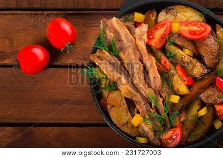 Fried Potatoes With Bacon And Fresh Tomatoes In The Frying Pan. Wooden Rustic Background. Top View.