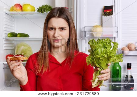 Discontent Female Frown Face, Has To Keep To Diet, Eats Only Fruits And Vegetables, Holds Lettuce An