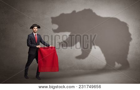 Businessman standing with red cloth in his hand and big bear shadow on his background