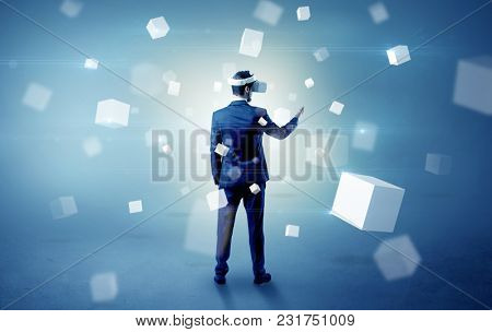Handsome businessman with vr goggle and falling white cubes around