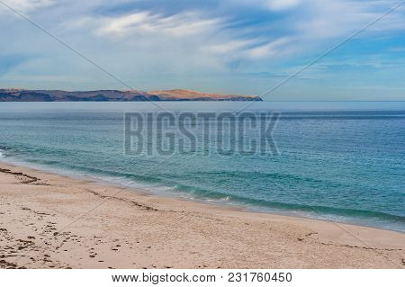 Calm Sea And Sand Beach With Distant Hills And Dolphin Backs In The Water On Clear Day. Picturesque 