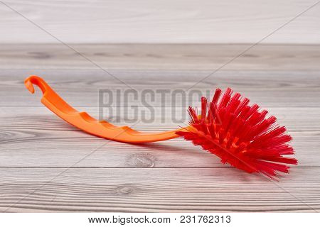 Red Brush For Washing Dishes. Close Up Cleaning Brush On Wooden Background. House Cleaning Supply.