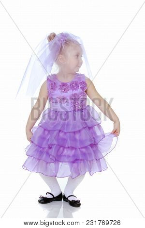 A Sweet Little Round-faced Girl In A Smart Purple Dress. With A Veil Covering His Face.she Makes A C