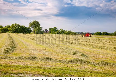 English rural landscape with  tractor collecting cut hay making silage bales Southern England UK
