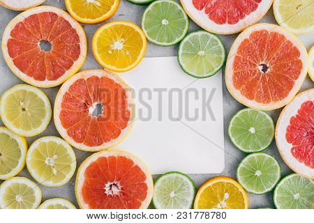 Top View Paper Sheet With Sliced Citrus Fruit On Light Background. Flat Lay. Summer Background