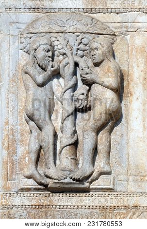 VERONA, ITALY - MAY 27: Adam and Eve eat the fruit of the forbidden tree, medieval relief on the facade of Basilica of San Zeno in Verona, Italy, on May 27, 2017.
