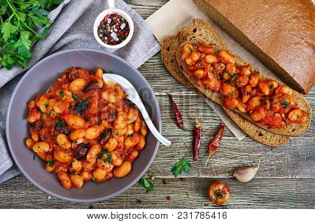 Stewed Broad Beans In Tomato Sauce With Herbs And Spices Closeup. Slices Of Rye Bread With Beans On 