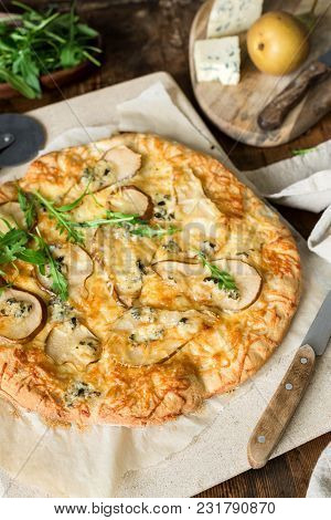 Pear And Blue Cheese Quatro Formaggi Pizza Garnished With Arugula On Baking Stone, Selective Focus