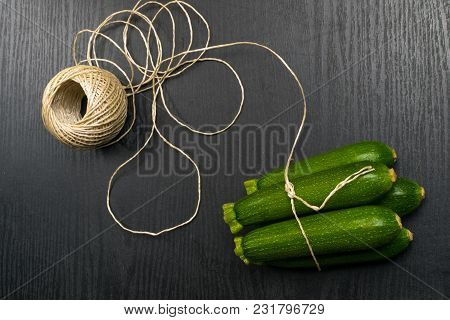 Top View Of Whole Mini Green Zucchini With Thread Over Dark Background.