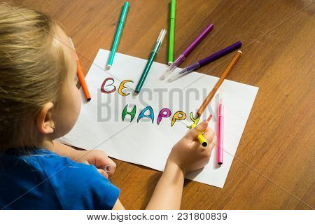 A Little Girl Writes, Paints With Felt-tip Pens Lying On The Floor. View From The Back