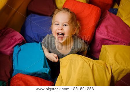 Cute Little Girl Laughing And Playing Among The Big Tissular Multi Colored Cubes In The Playing Room
