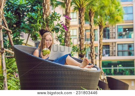 Young Female Freelancer Sitting Near The Pool With Her Laptop. Busy At Holidays. Distant Work Concep