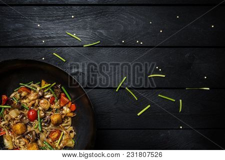 Udon Stir Fry Noodles With Meat Or Chicken And Vegetables With Tofu. In Wok Pan On Black Wooden Back