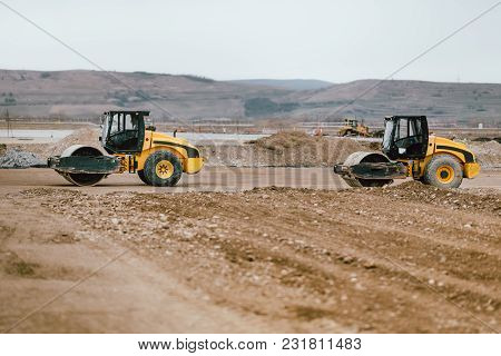 Two Vibratory Soil Compactors During Road And Highway Construction. Industrial Roadworks With Heavy-
