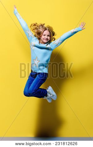 Joyful pre-teen girl jumping over yellow background. Full length studio shot. Happiness, activity and child concept.